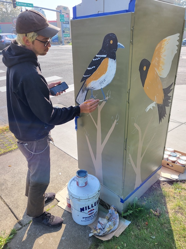 Man painting bird on electrical box