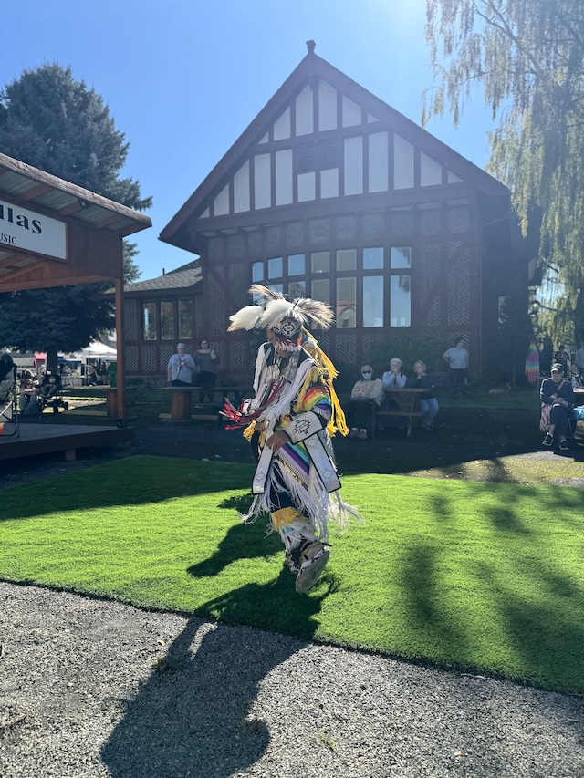 A Native dancer in white regalia performing.