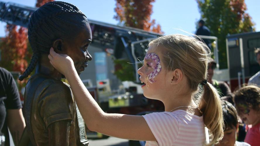 Girl examines female statues ear.